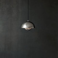 Silver dome pendant light against a dark textured wall, featuring a sleek and modern design.