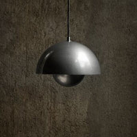 Modern black and silver pendant lamp with a sleek, half-dome shape against a textured dark background.