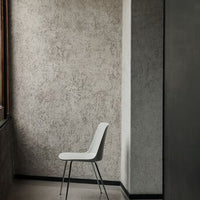 Minimalist white chair against a textured gray wall, highlighting modern design and subtle color contrasts.