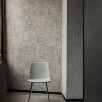 Light gray modern chair against a textured gray wall in a minimalist setting. Stylish and versatile decor piece.