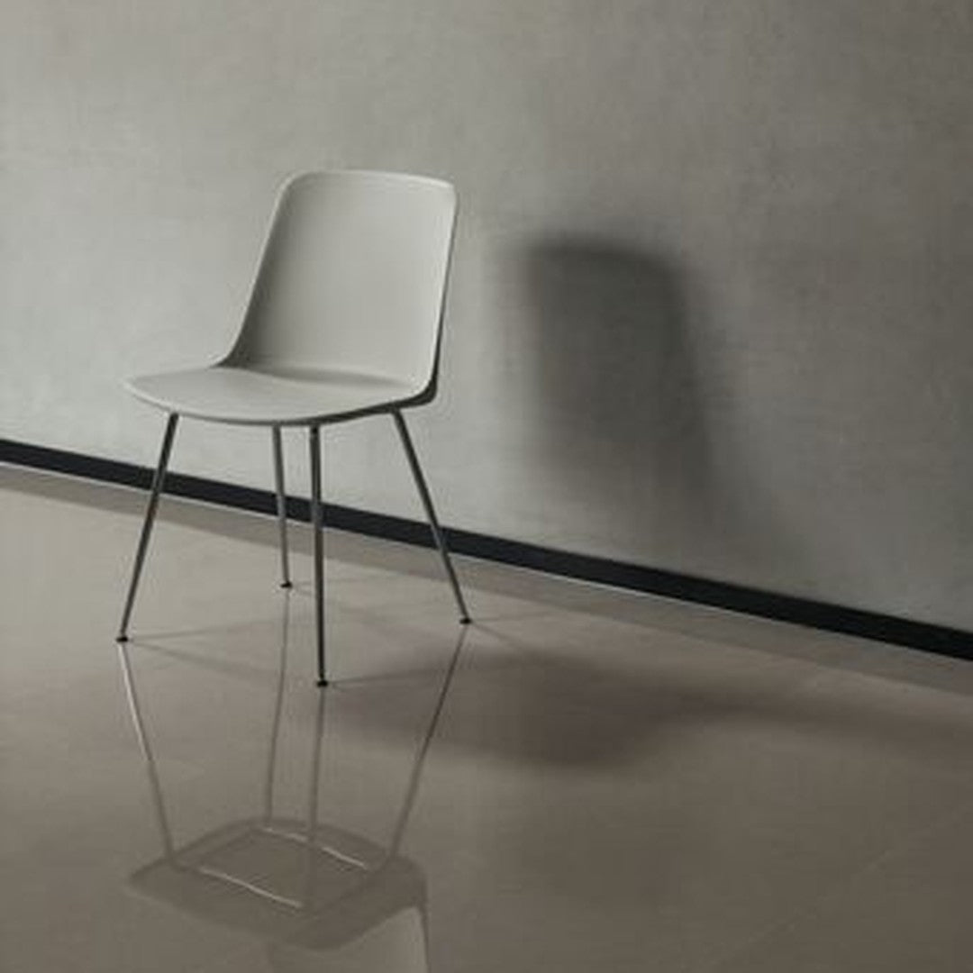Sleek gray chair with a minimalist design, set against a concrete wall and glossy floor, showcasing modern simplicity.