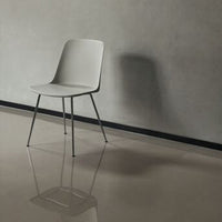 Sleek gray chair with a minimalist design, set against a concrete wall and glossy floor, showcasing modern simplicity.