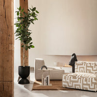 Beige and cream patterned cushions with geometric designs, set in a modern, minimalistic interior with greenery.