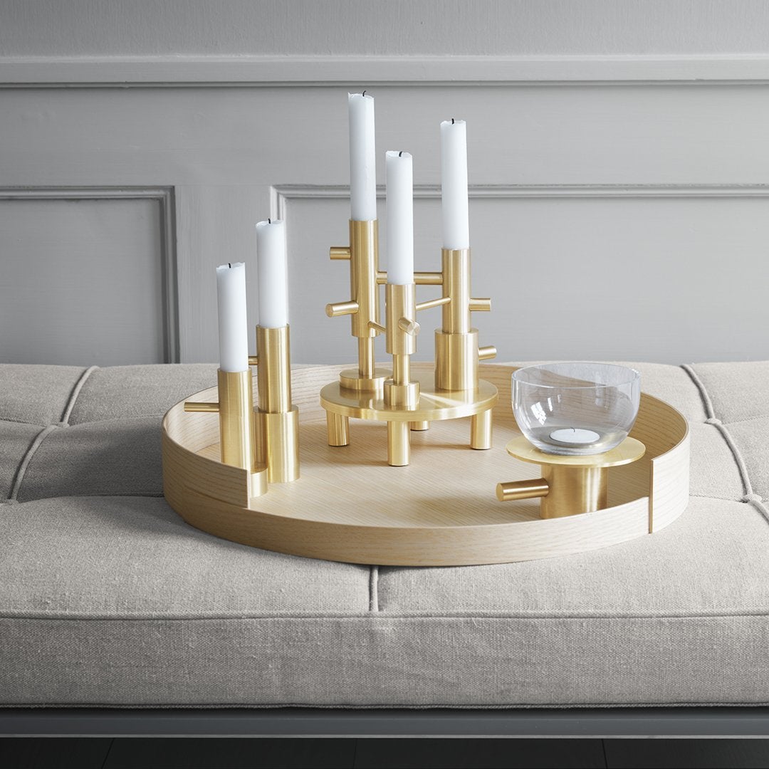 "Chic gold candle holder with white candles on a beige circular tray, perfect for modern home decor."