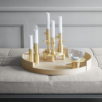 "Chic gold candle holder with white candles on a beige circular tray, perfect for modern home decor."