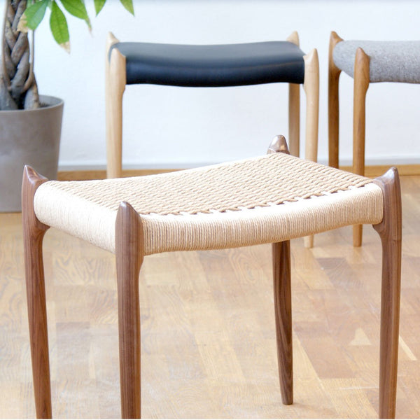 Natural woven seat in beige, wooden legs in walnut finish; two additional stools in black and gray. Modern design.