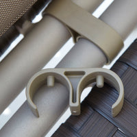 Beige plastic clip with a smooth surface, designed to attach to light-colored metal poles and woven patterns.