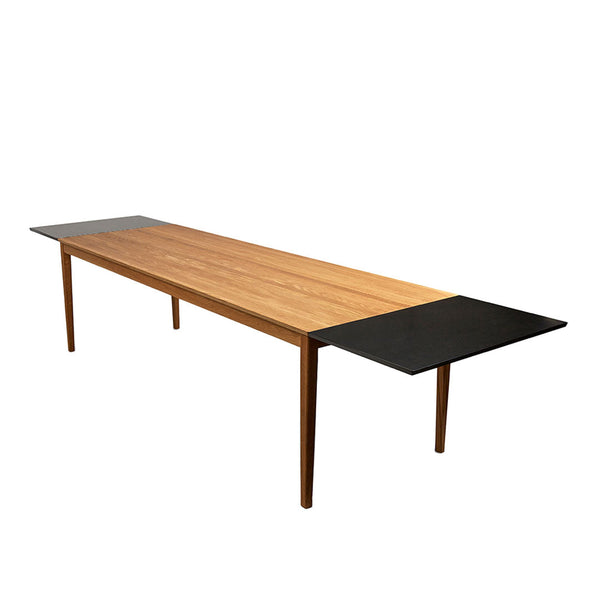 Modern wooden dining table with a warm oak finish and sleek black accents on the sides. Ideal for contemporary decor.
