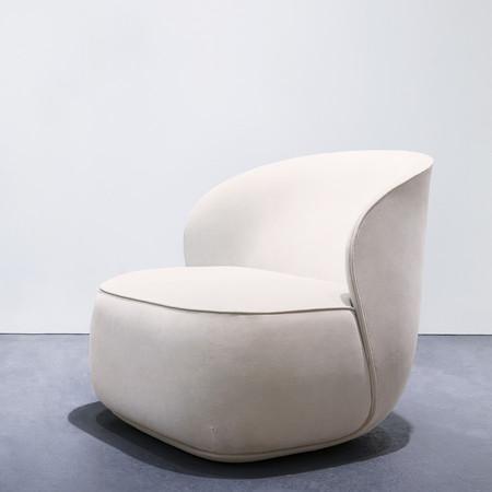 Soft beige accent chair with a smooth, curved design and minimalistic pattern, perfect for modern decor.