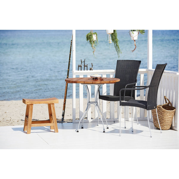 "Wooden patio table with black chairs, paired with a natural wood stool, set against a serene beach backdrop."
