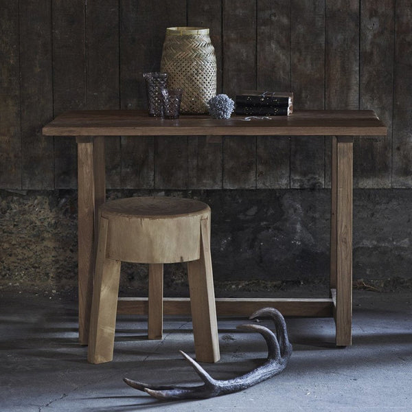 Brown wooden table and stool with a rustic finish, accented by natural textures and muted earth tones.