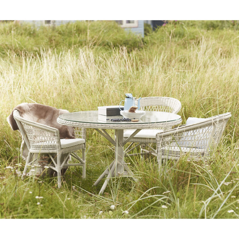 Round patio table and wicker chairs with a light gray finish, complemented by soft, earthy tones and subtle textures.