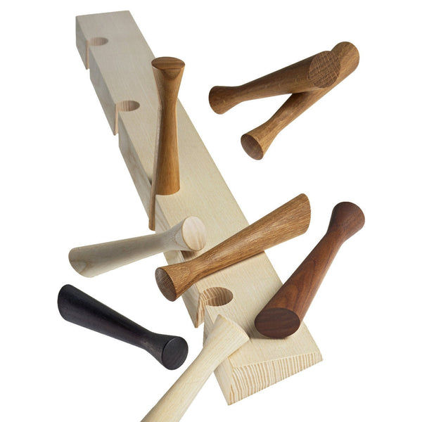 Assorted wooden pegs in natural, light beige, dark brown, and black on a light wooden board with hole patterns.