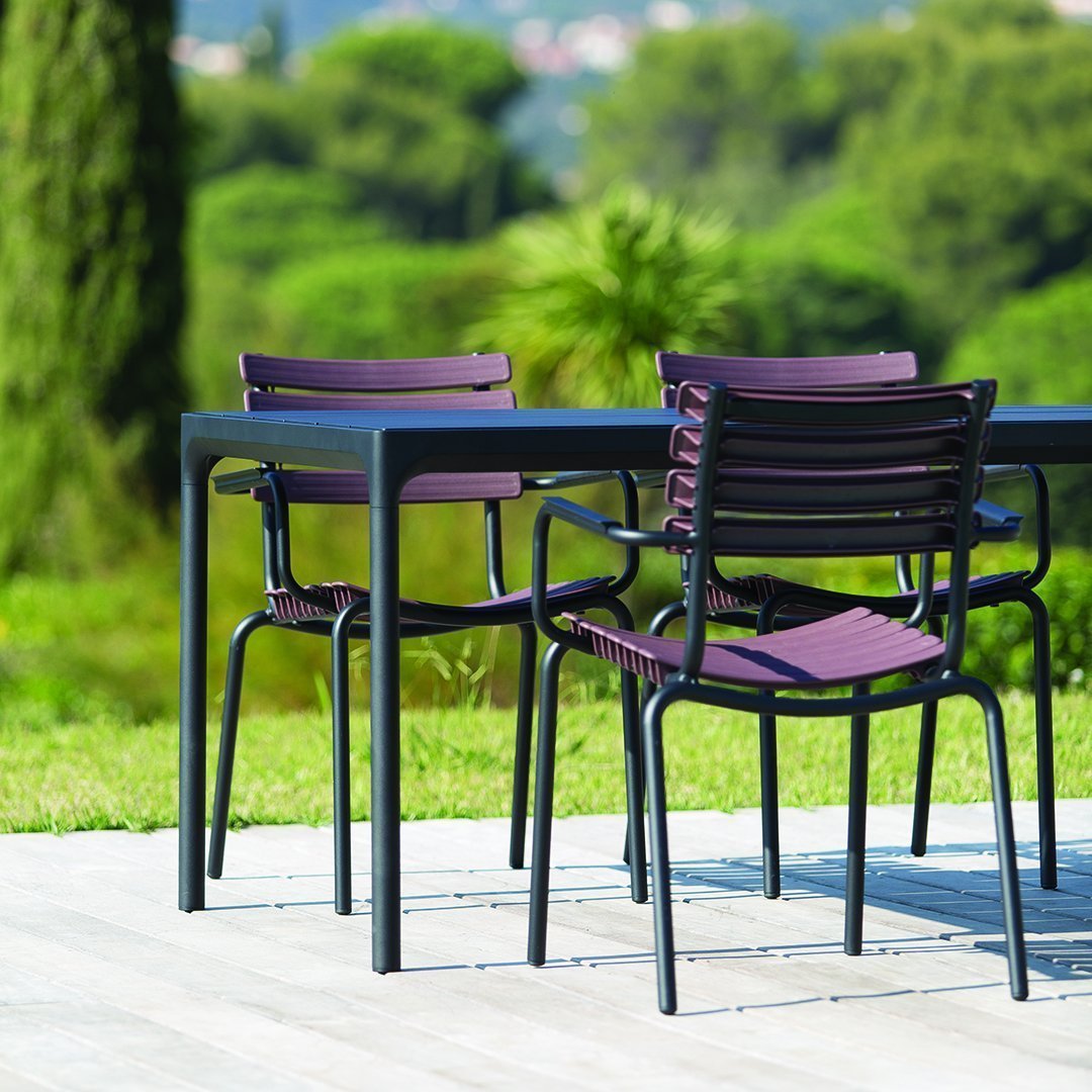Purple and black dining chairs with a sleek design, set against a lush green landscape. Perfect for outdoor gatherings.