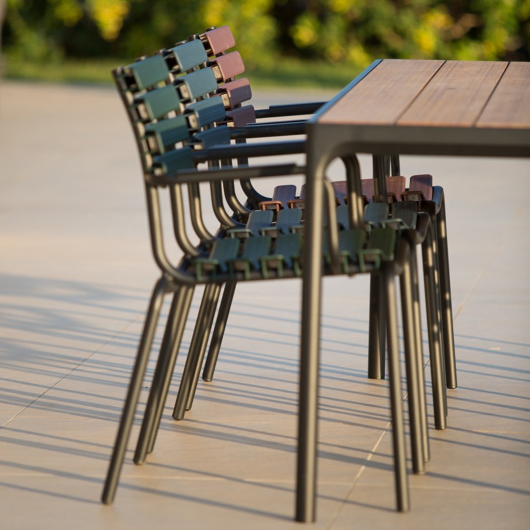 Colorful stackable chairs featuring green, blue, and maroon patterns beside a wooden table. Perfect for outdoor settings.