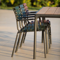 Colorful stackable chairs featuring green, blue, and maroon patterns beside a wooden table. Perfect for outdoor settings.