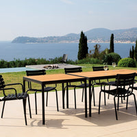 "Elegant black metal outdoor dining set with sleek lines and a warm wooden tabletop in a sunny coastal setting."