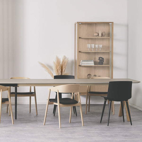 Elegant dining setup featuring black and natural wood chairs, with a minimalist aesthetic and neutral color palette.