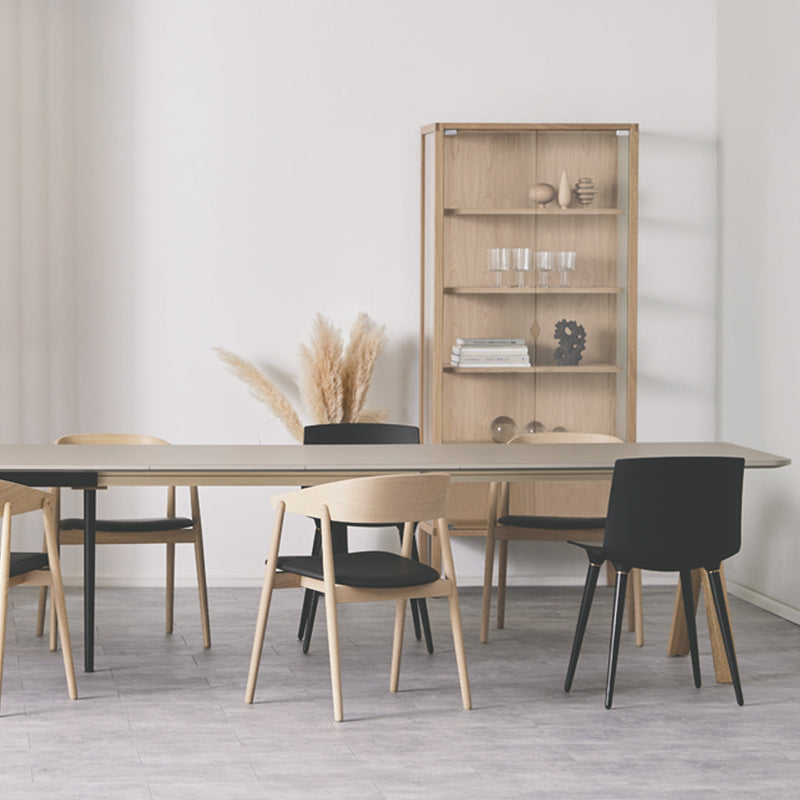 Elegant dining setup featuring black and natural wood chairs, with a minimalist aesthetic and neutral color palette.