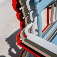Colorful stackable chairs featuring red, blue, beige, and gray hues with sleek, modern lines and patterns.