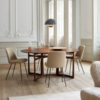 Modern round wooden dining table with beige textured chairs, complemented by a sleek black pendant light.