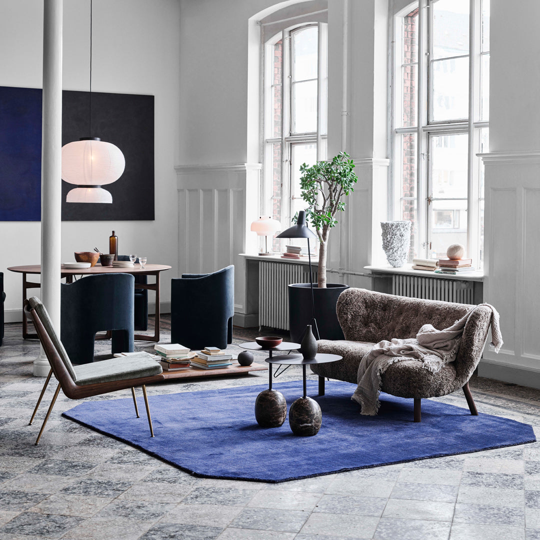 Cozy living room featuring navy blue rug, gray furniture, green plant, and geometric patterns on the floor.