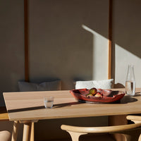 Warm wood tones with a sleek, modern design. Earthy red bowl with vibrant fruit against a soft, neutral backdrop.