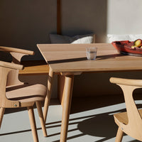 Light wood dining table and chairs with a natural finish, highlighting smooth textures and warm, earthy tones.