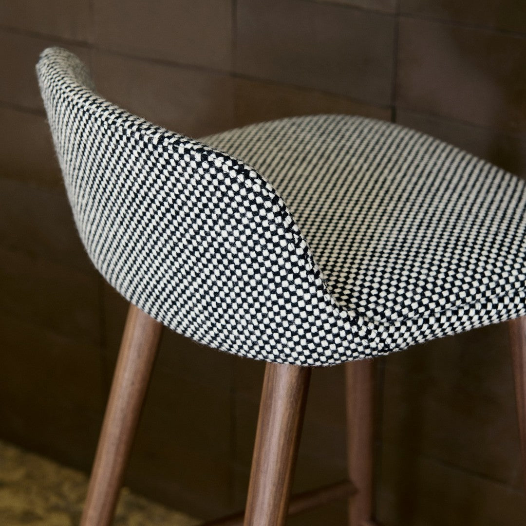 Black and white houndstooth pattern upholstery on a modern bar stool with wooden legs.