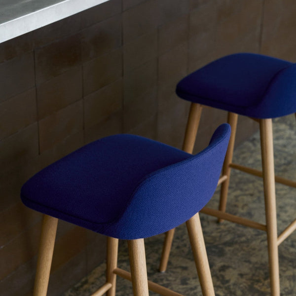 Navy blue upholstered bar stools with light wood legs and a modern design, perfect for any contemporary space.