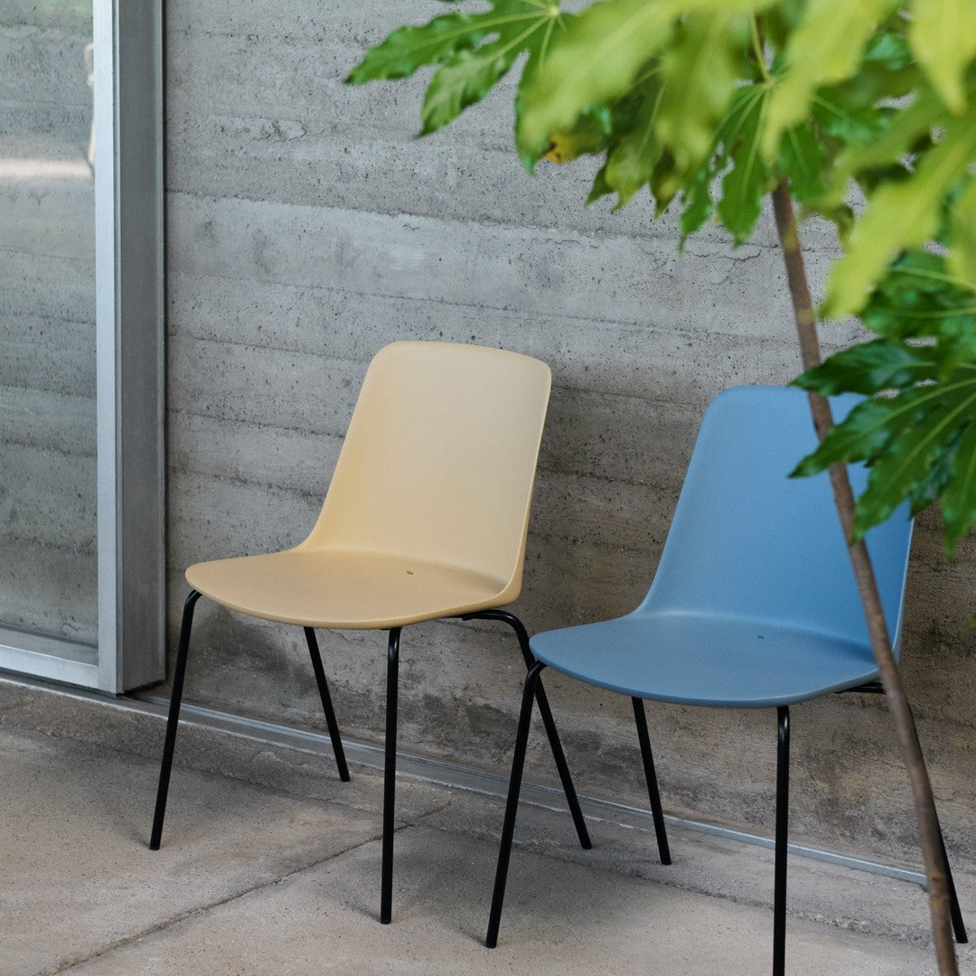 "Minimalist chairs in soft yellow and blue with sleek black legs, perfect for modern decor."
