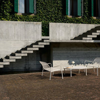 Concrete steps with a minimalist design, surrounded by vibrant green ivy and a textured brown patio surface.