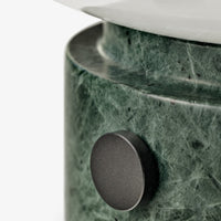 Green marble base with subtle veining and a sleek black accent button on a minimalist design.