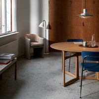 Modern dining room with a round wooden table, blue chairs, and beige accents in a minimalist, warm color palette.