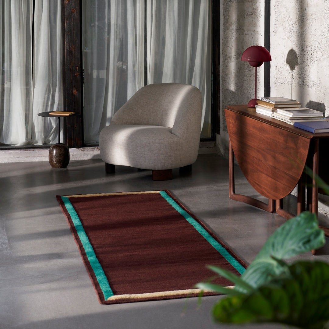 Brown area rug with teal and beige borders, featuring a modern geometric pattern, ideal for contemporary decor.