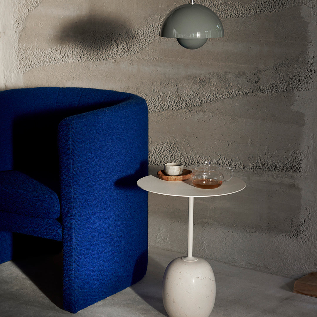 Vibrant blue upholstered chair with a white side table and soft gray walls, creating a modern, cozy atmosphere.