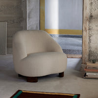 Cream-colored upholstery with a soft, textured pattern on a modern, rounded armchair. Elegant wooden base complements design.