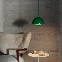 Green pendant lamp with a smooth, rounded design, paired with a cozy cream chair and minimalist white table.
