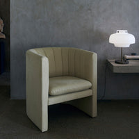 Modern olive green barrel chair with vertical stitching against a muted gray background. Ideal for contemporary decor.