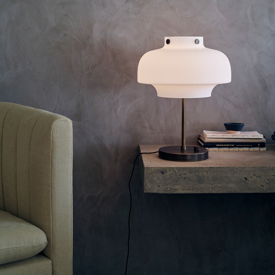 Modern white lamp with a matte finish, paired with dark wood and a grey-toned wall, enhancing minimalist aesthetics.