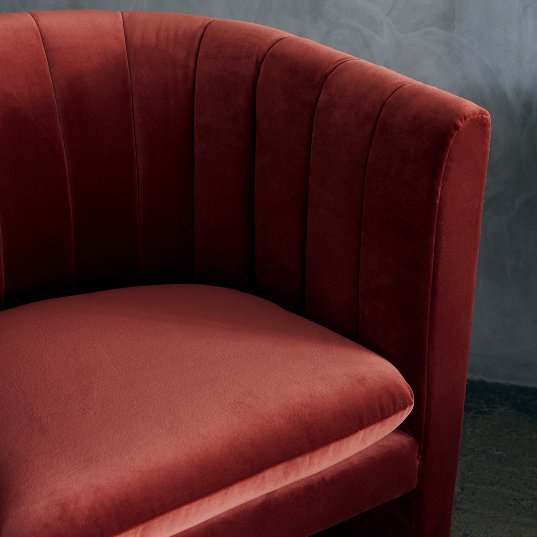 Velvet armchair in rich burgundy with vertical tufted pattern, adding elegance to any space.