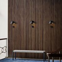 Elegant black wall sconces against a rich wood-paneled backdrop with a blue carpet and a minimalist white bench.