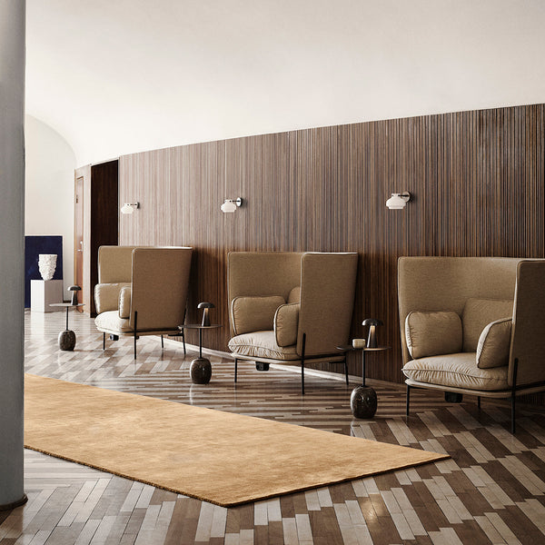 Beige and tan rug on a patterned wooden floor with a modern, minimalist interior design.
