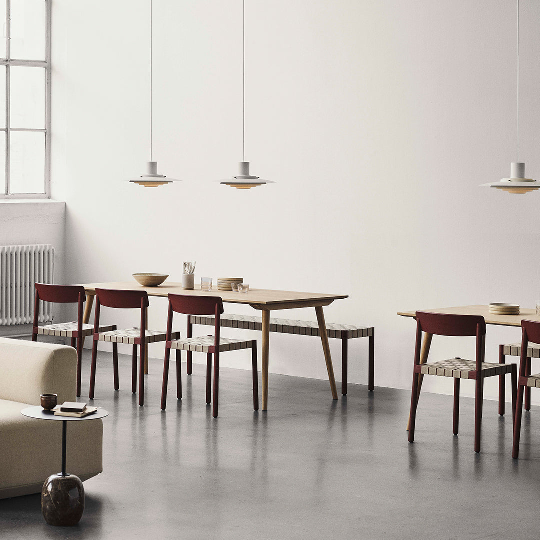 "Modern dining room with natural wood tones, red chairs, and minimalist gray decor, featuring soft lighting."