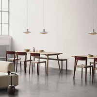 "Modern dining room with natural wood tones, red chairs, and minimalist gray decor, featuring soft lighting."