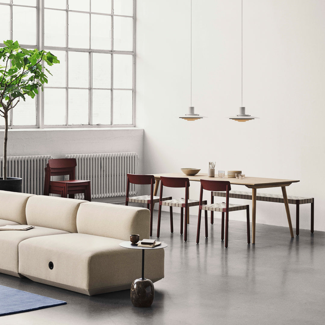 "Modern living room features light beige sofa, dark wood dining set, and green plant against neutral backdrop."