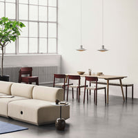 "Modern living room features light beige sofa, dark wood dining set, and green plant against neutral backdrop."