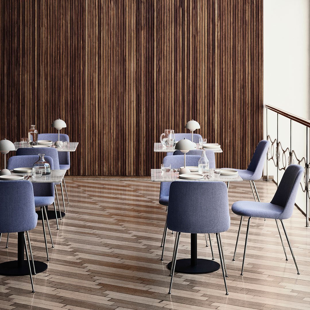 Stylish dining area featuring soft purple chairs against a warm wood-paneled wall and geometric patterned floor.