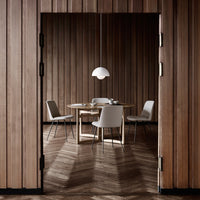 Elegant wooden interior featuring herringbone flooring, soft gray chairs, and a simple white pendant light.