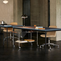 Modern desk with a sleek black surface, accented by warm wood tones and beige seating, set in a minimalist space.